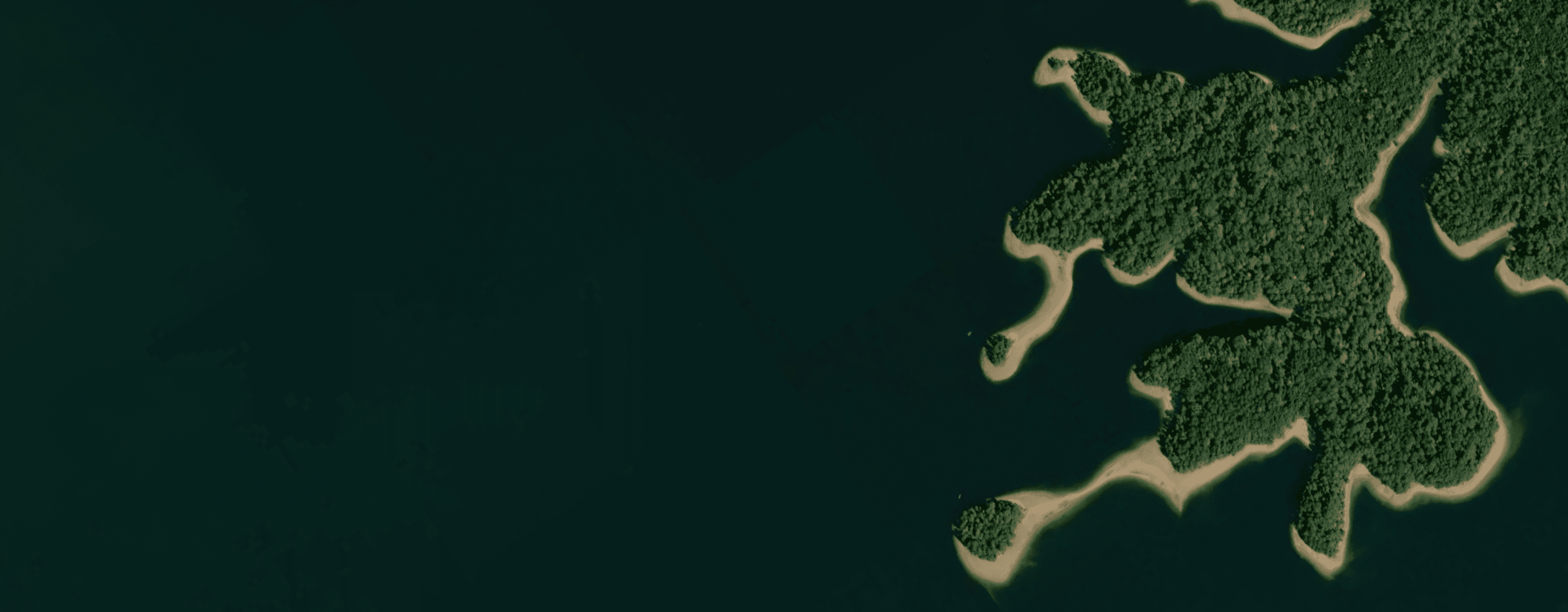 Angler overlooking a broad island-dotted freshwater reservoir at sunrise.